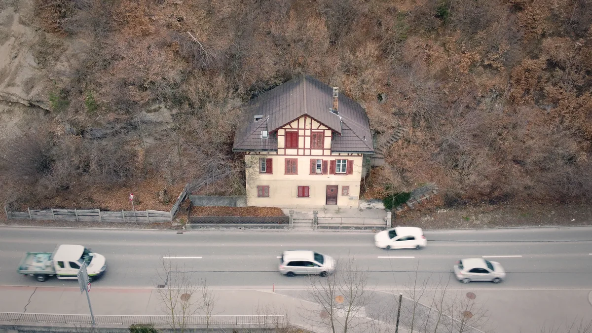 Ein Haus steht direkt an einer Strasse.
